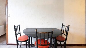 Una mesa de comedor con cuatro sillas, una pared lisa y una esquina con un radiador.