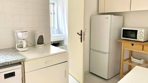 A compact kitchen with a refrigerator, microwave, coffee maker, and a wooden table. - Central Avenue #1 (Lisboa)