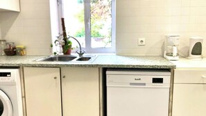 A kitchen with a built-in dishwasher, a sink, and a window with a view of greenery outside. - Central Avenue #1 (Lisboa)