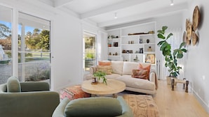 Ein modernes Wohnzimmer mit einer Couch, Sesseln, einem Couchtisch und einem Bücherregal.