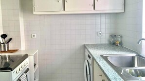 A kitchen with white cabinets, a washing machine, a stove, and a sink. - Central Avenue #2 (Lisboa)
