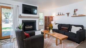 Ein Wohnzimmer mit Kamin, Fernseher, einer Couch und einem Couchtisch.