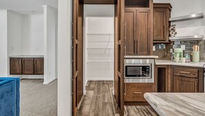 A compact kitchen with wooden cabinets, a microwave, and a small countertop. - Welcoming 3-bedroom home with jacuzzi (Winterport)