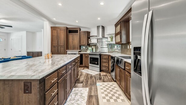 A modern kitchen with wooden cabinets, a stainless steel refrigerator, and a marble island. - Welcoming 3-bedroom home with jacuzzi (Winterport)