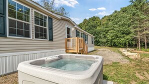A house with a hot tub, wooden deck, and a stone pathway. - Welcoming 3-bedroom home with jacuzzi (Winterport)
