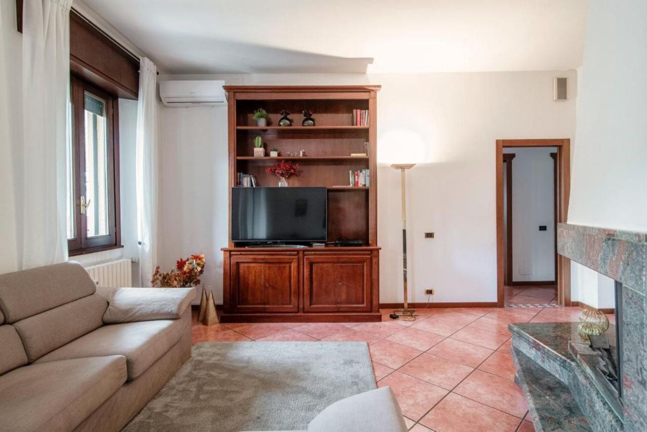 A living room with a sofa, a TV on a wooden cabinet, a lamp, and a fireplace.