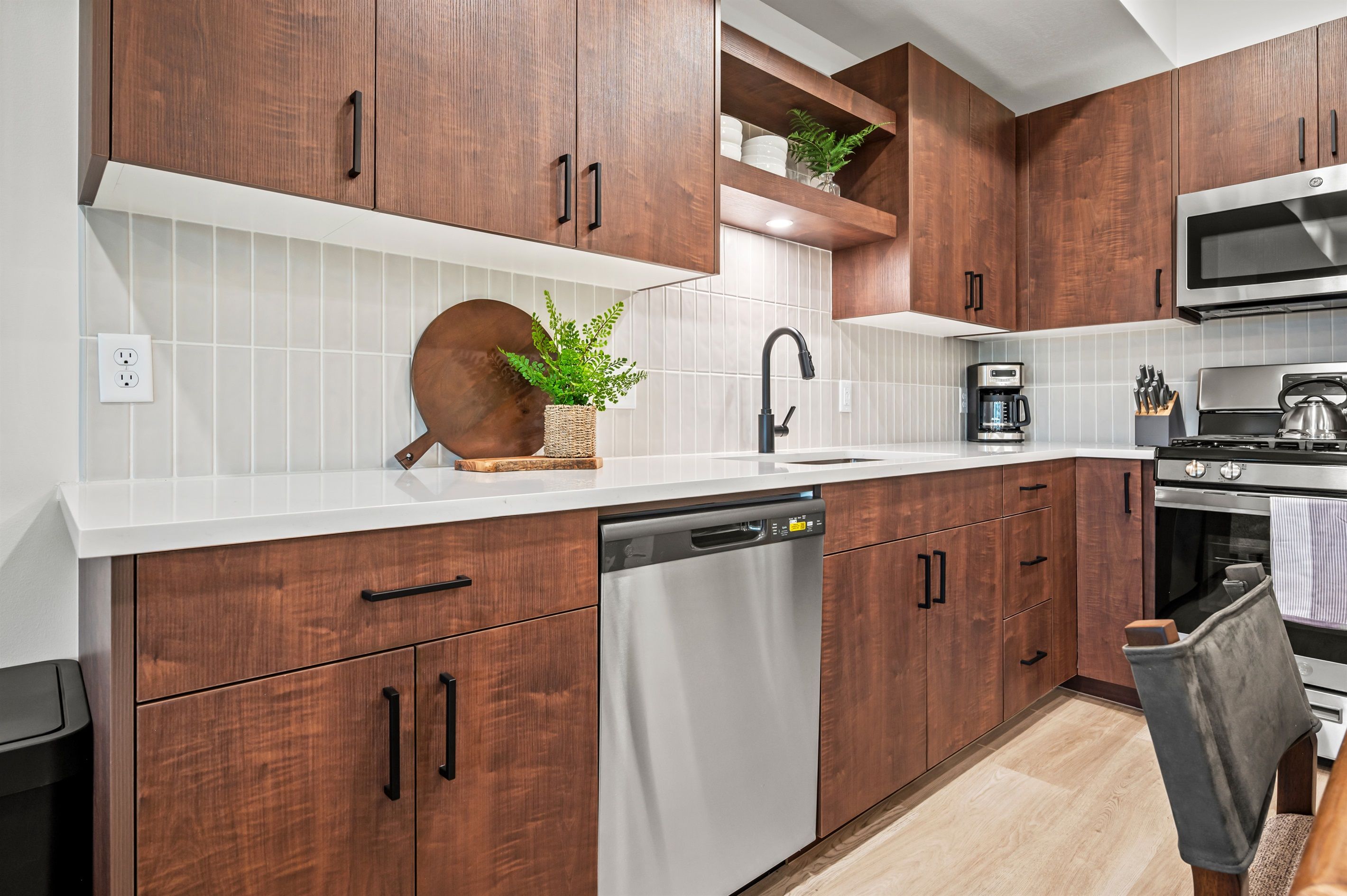 Una cocina moderna con armarios de madera, lavavajillas, microondas y cafetera.