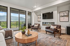 A modern living room with a fireplace, leather sofas, a coffee table, and a large TV.