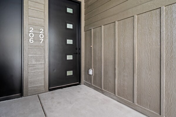 A modern building entrance with a black door marked with the numbers 206 and 207.