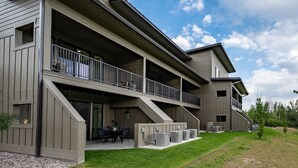Un edificio de varios pisos con balcones, mobiliario exterior y unidades de aire acondicionado.