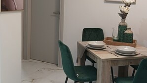 A dining area with a wooden table, green upholstered chairs, and a vase with flowers.