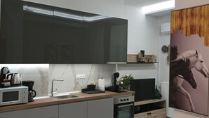 A modern kitchen with dark cabinets, a marble backsplash, and a wooden countertop.