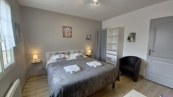 Une chambre à coucher avec un lit, des lampes de chevet, une chaise, une armoire et une porte.