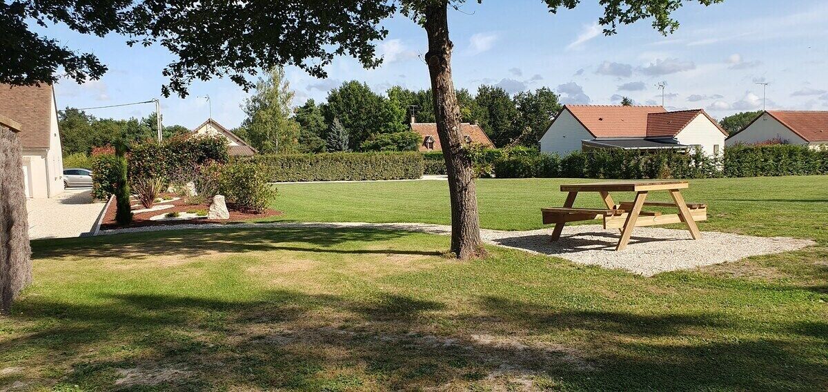 Un espacio al aire libre con césped, una mesa de picnic y un árbol.
