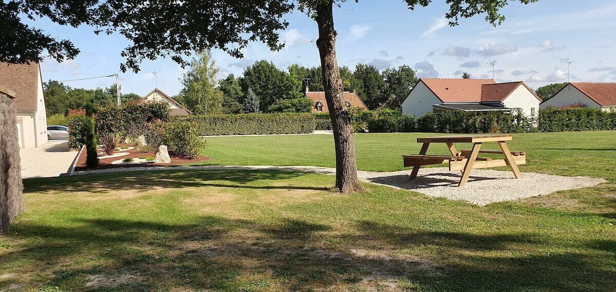 Un espace extérieur verdoyant avec une table de pique-nique et un arbre.