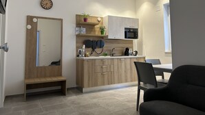 A modern kitchen with wooden cabinets, a microwave, and a sink. There is a bench and a chair in the room. - Borgo di Levante Apt1 (Brindisi)