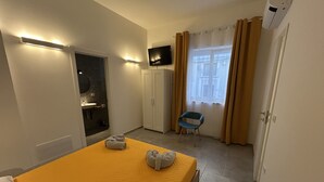A hotel room with a bed, a TV, a chair, and a window with curtains. - Borgo di Levante Apt1 (Brindisi)