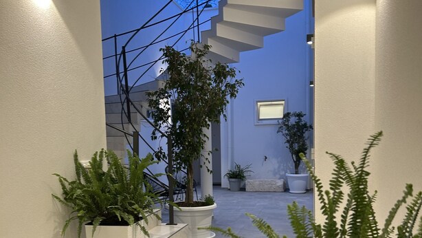 A modern hallway with a skylight, potted plants, and a staircase leading to a second floor. - Borgo di Levante Apt1 (Brindisi)