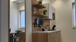 A modern kitchen with wooden cabinets, a built-in bench, a microwave, and a potted plant on a shelf. - Borgo di Levante Apt1 (Brindisi)