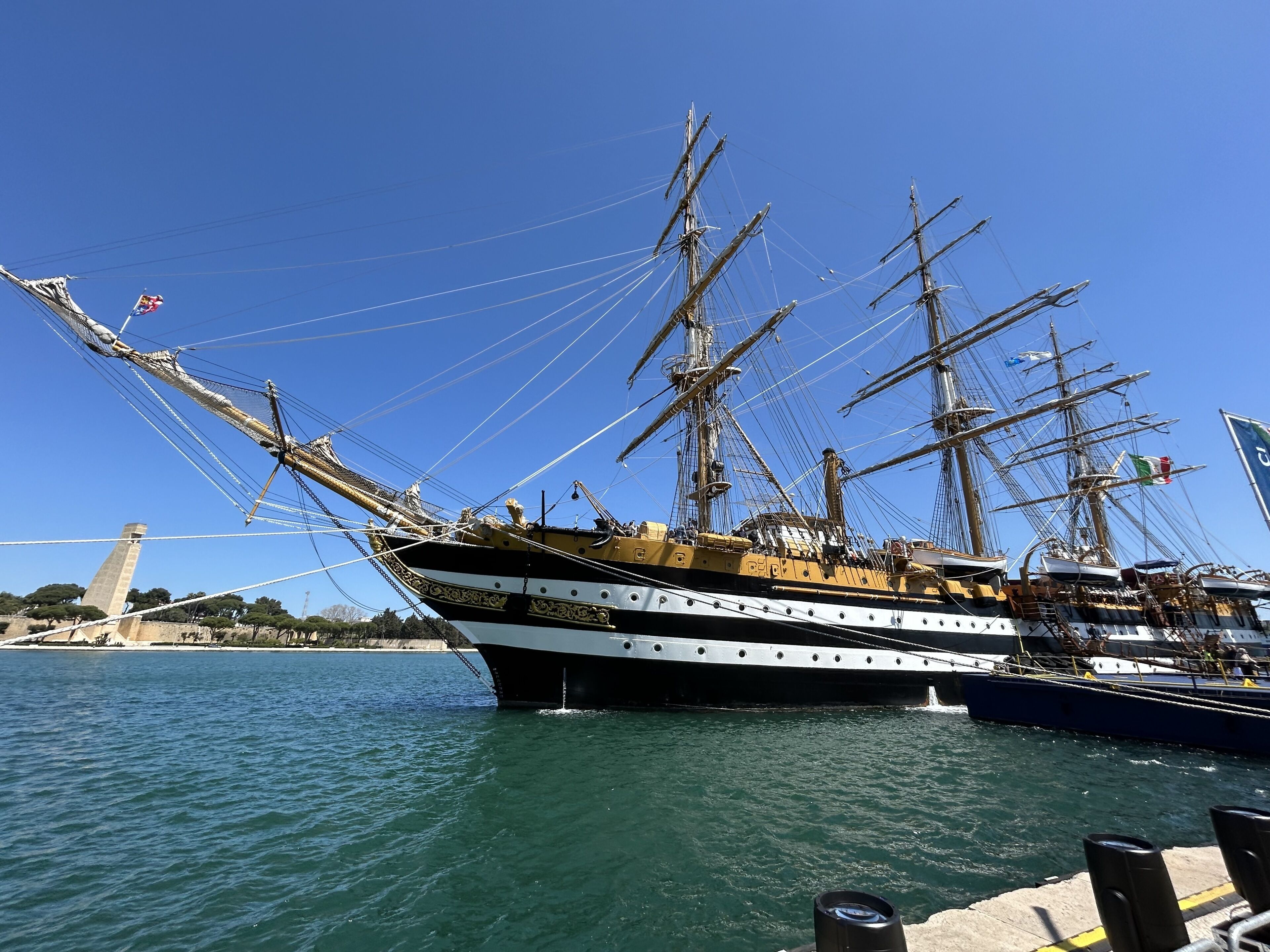 A large sailing ship docked at a harbor with a clear sky.