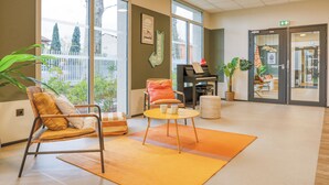 Un vestíbulo espacioso con ventanas amplias, un piano, asientos cómodos y vistas al exterior.