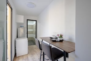 Une cuisine de taille réduite avec une table en bois, des chaises et un petit réfrigérateur.