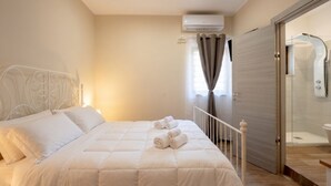 Une chambre à coucher avec un lit, une fenêtre avec des rideaux, un appareil de climatisation et une porte de douche en verre.