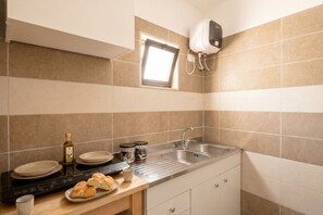 Une cuisine équipée d’une cuisinière intégrée, d’une fenêtre, d’un évier et de placards.