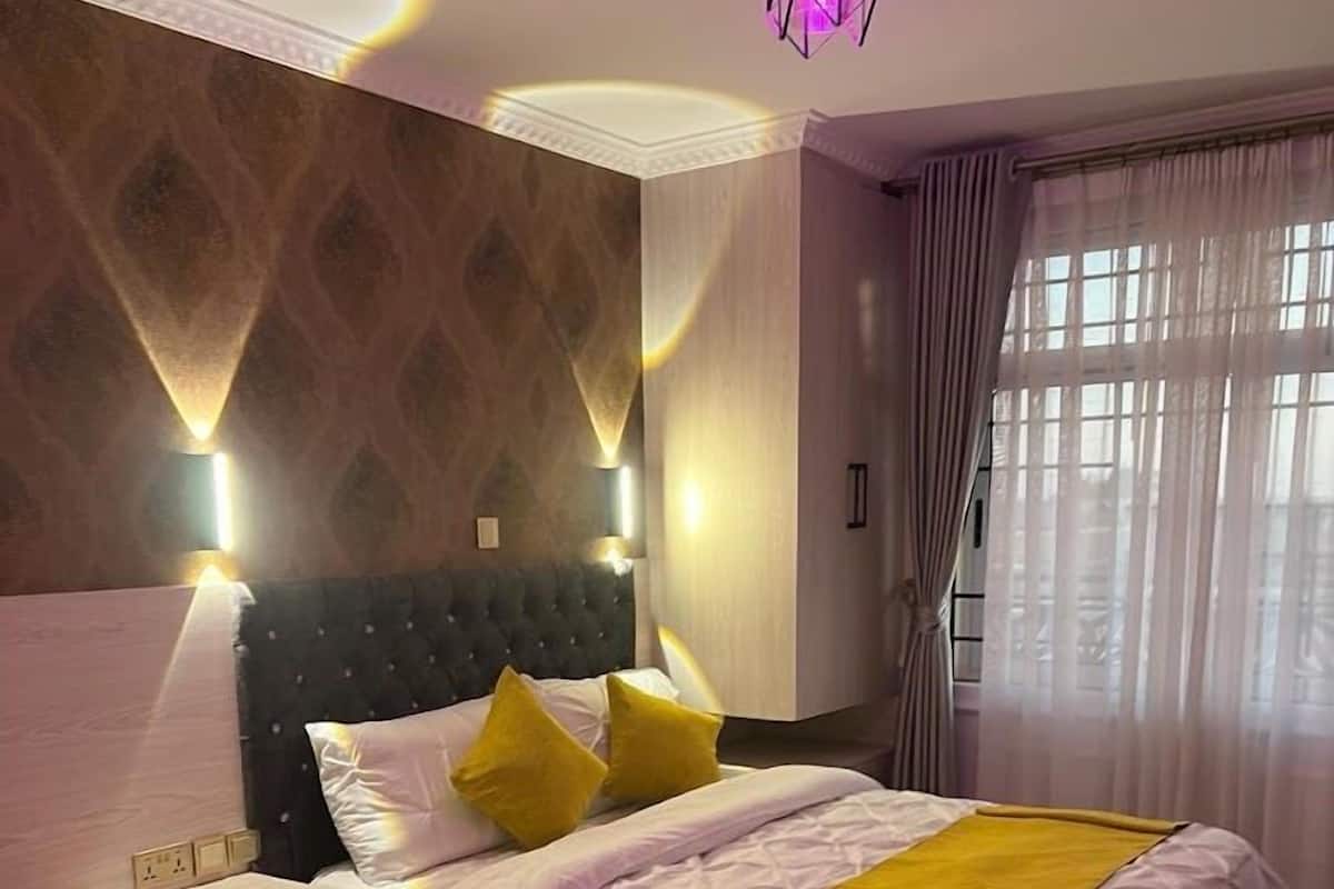 Un dormitorio moderno con una cama grande, mesitas de noche y una lámpara decorativa en la pared.