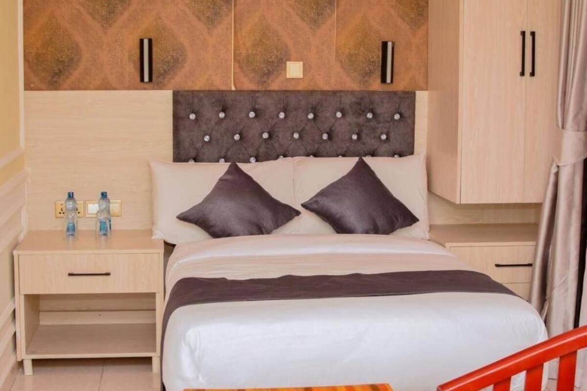 Una habitación de hotel con cama, mesitas de noche y un armario.