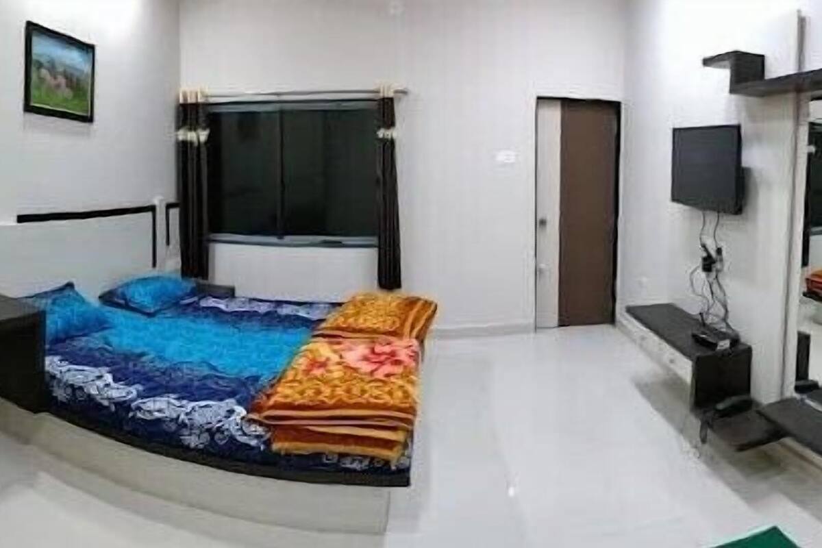 Ein Schlafzimmer mit Bett, Schreibtisch, Stuhl, Fenster, Tür und Fernseher.
