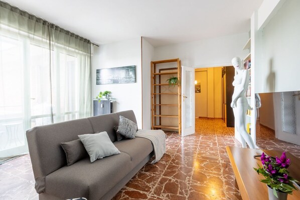 Una sala de estar moderna con un sofá, un maniquí y una estantería.