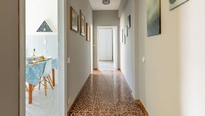 Un pasillo con suelo estampado, cuadros enmarcados en las paredes y una mesa con sillas al fondo.