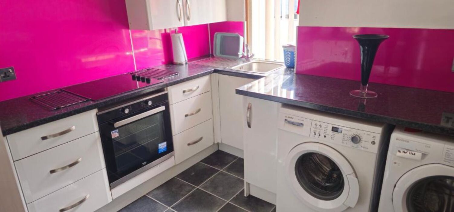 A compact kitchen with a microwave, oven, and washing machine.