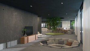 Un salon moderne avec un grand téléviseur, un espace salon circulaire et un petit jardin.