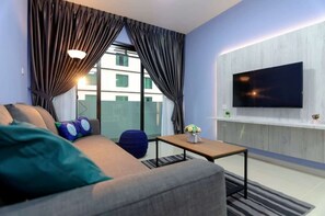 Een moderne woonkamer met een bank, een salontafel en een flatscreen televisie aan de muur.