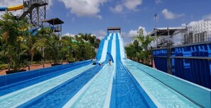 A water slide with multiple lanes, surrounded by palm trees and a clear sky. - Cozy JB Suasana 15 Suite, City Views (Johor Bahru)
