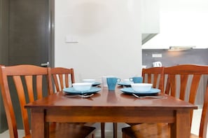 A dining table with chairs, a blue cup, and a white cup set for a meal. - Cozy JB Suasana 15 Suite, City Views (Johor Bahru)