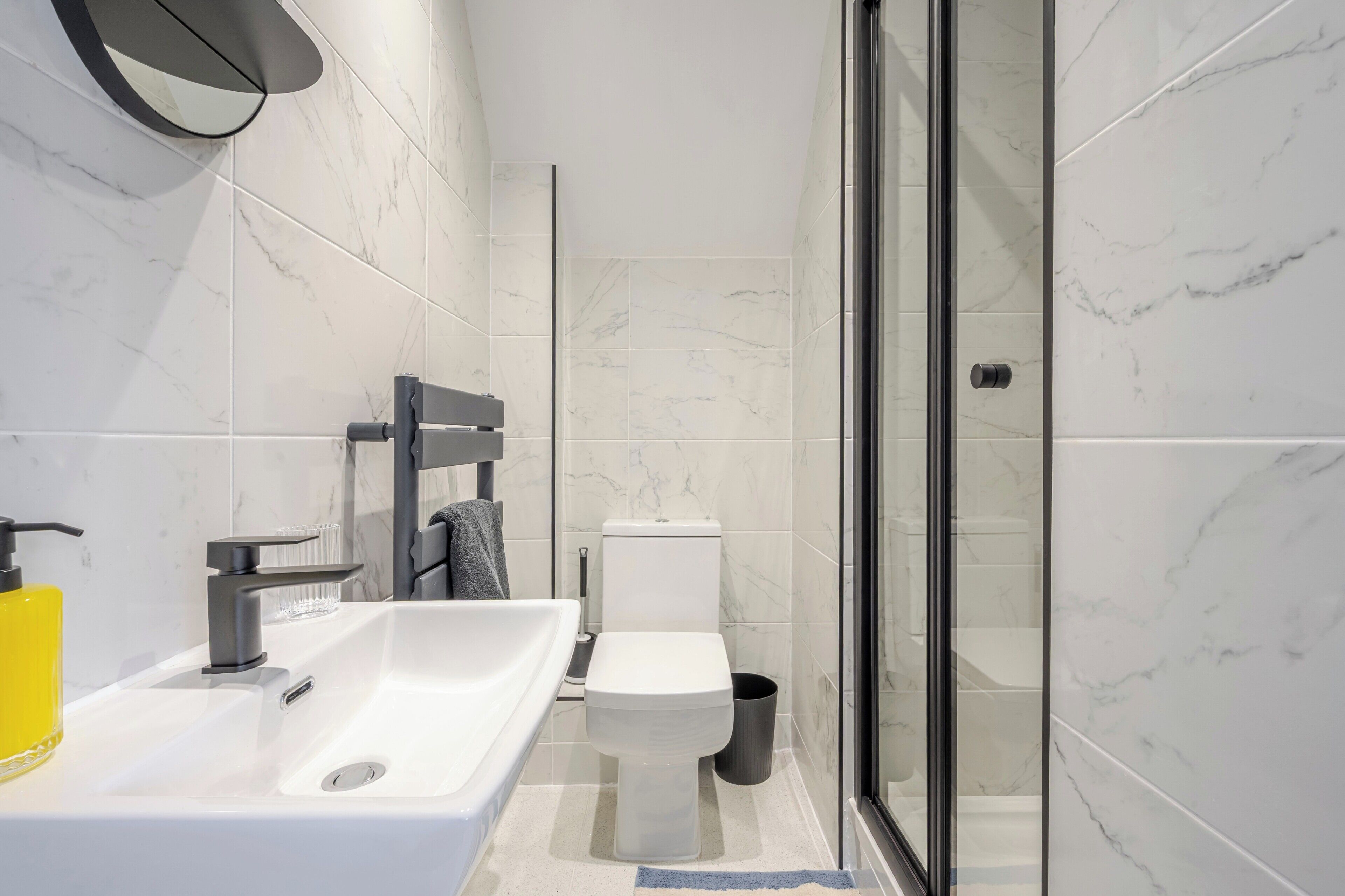 A modern bathroom with a white sink, toilet, and glass shower enclosure.