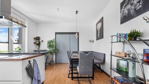 A modern kitchen with a dining area, wooden flooring, and a view of the outdoors.