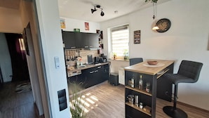 A modern kitchen with black cabinets, a wooden countertop, and a dining area with a table and chairs.