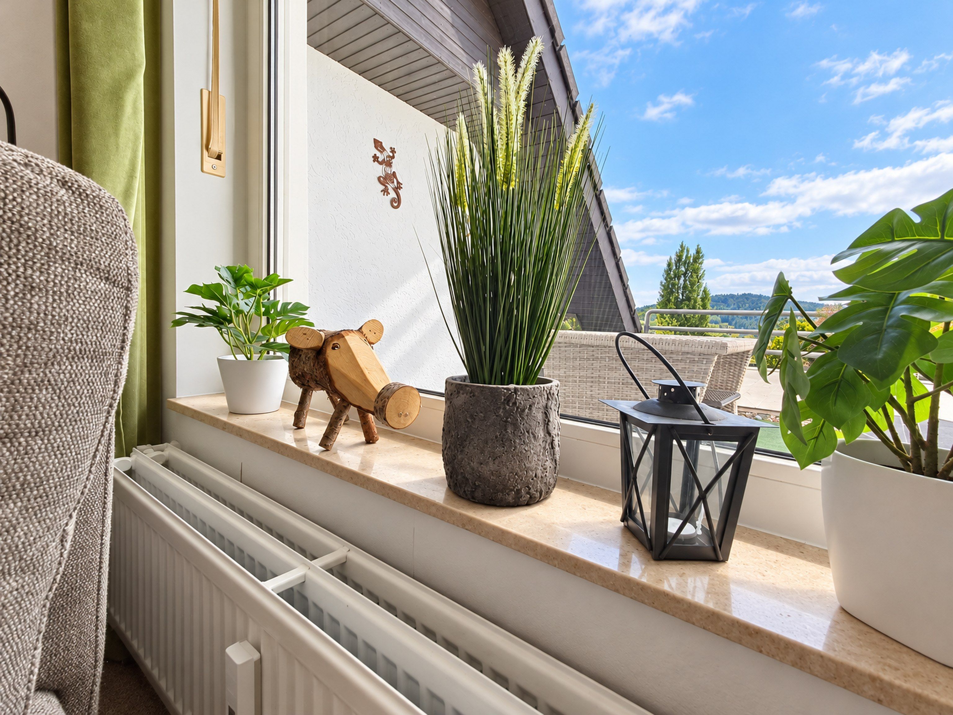 Un balcón con plantas en macetas, una escultura de madera y un farol.