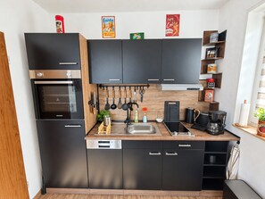 Cocina compacta con horno integrado, cafetera y lavabo.