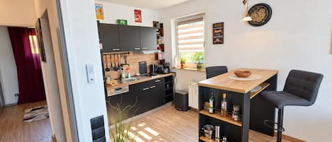 A modern kitchen with wooden cabinets, a dining table, and bar stools.