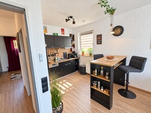 A modern kitchen with wooden cabinets, a dining table, and bar stools.