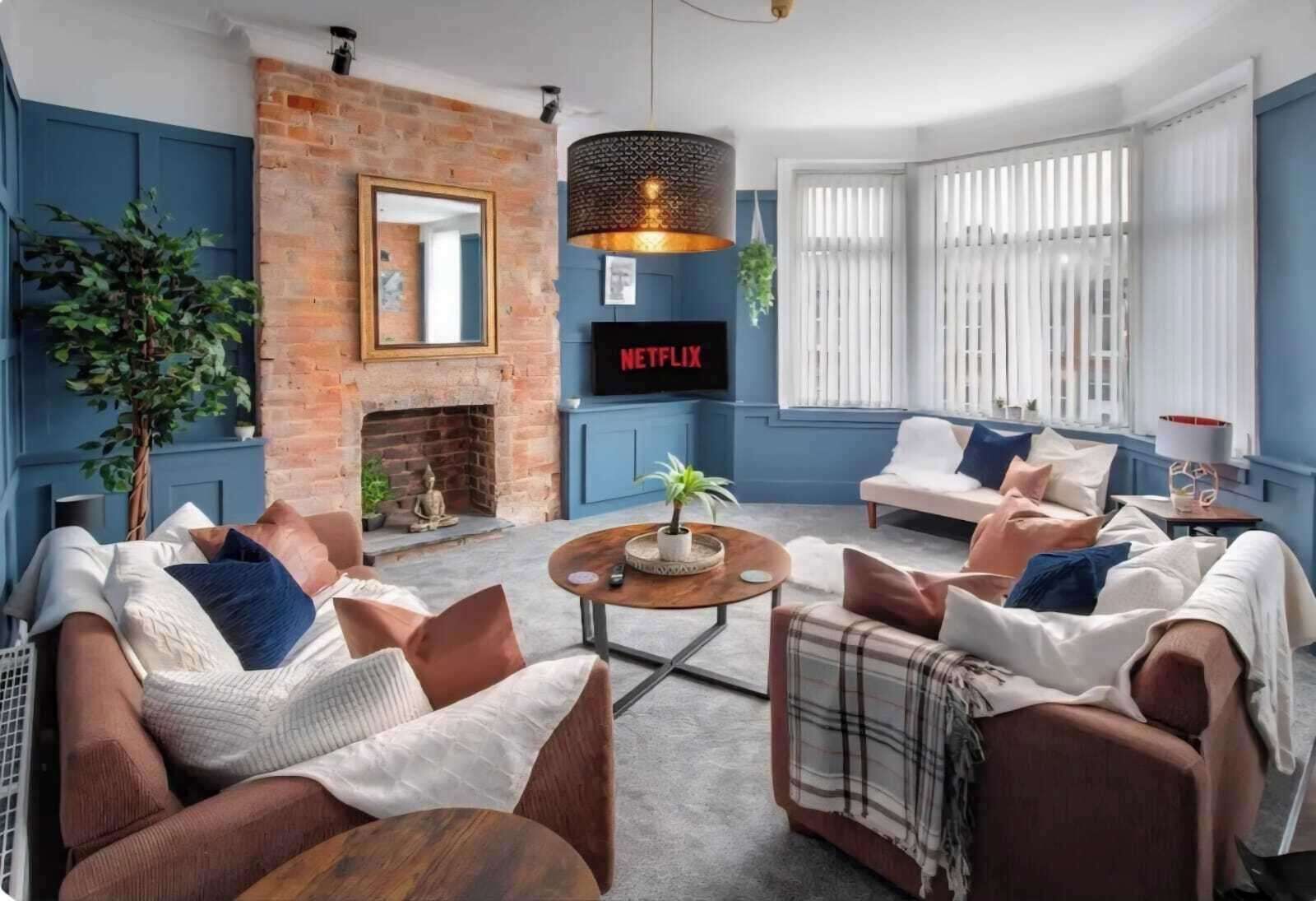 Uma sala de estar moderna com lareira de tijolos, TV com Netflix e assentos confortáveis.