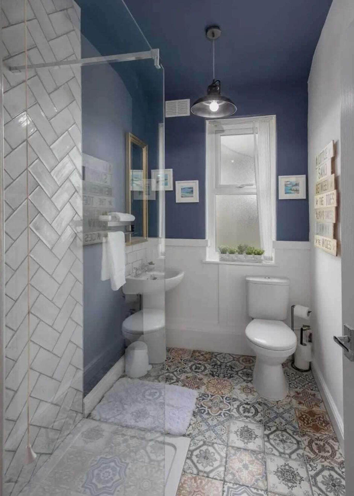 Un bagno con un motivo a spina di pesce nelle piastrelle, un lavandino bianco, un water e una zona doccia.