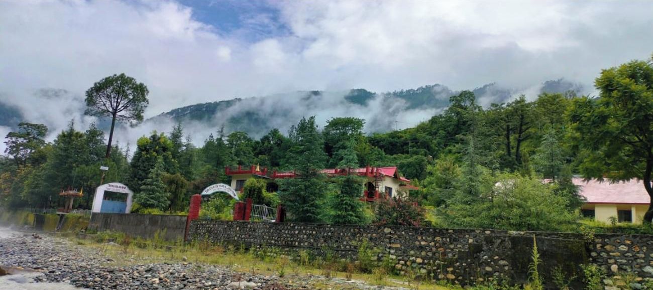 A rural setting with a stone wall, a small building with a red roof, and a sign that reads "Hotel."