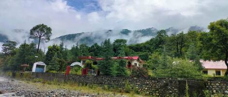 A rural setting with a stone wall, a small building with a red roof, and a sign that reads "Hotel."
