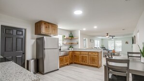 A modern kitchen with wooden cabinets, a stainless steel refrigerator, and a granite countertop.